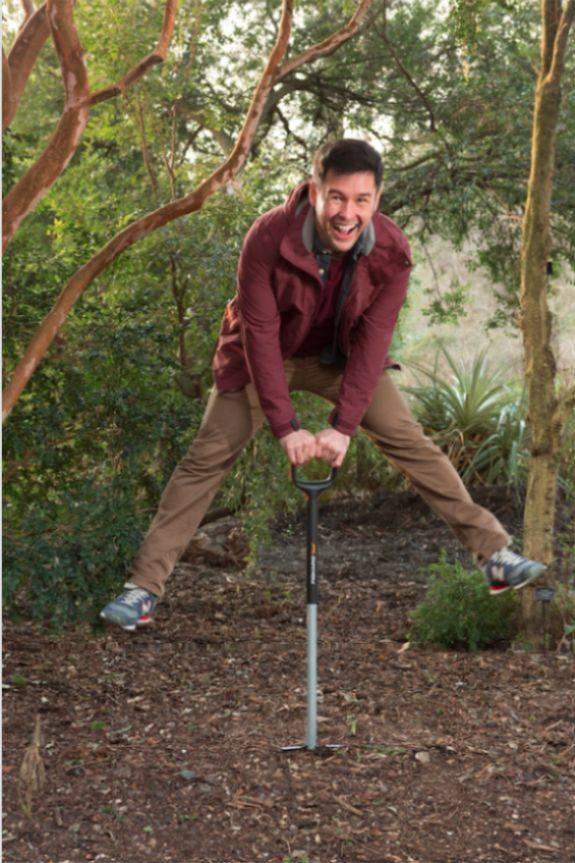 Man holding a spade and doing a star jump